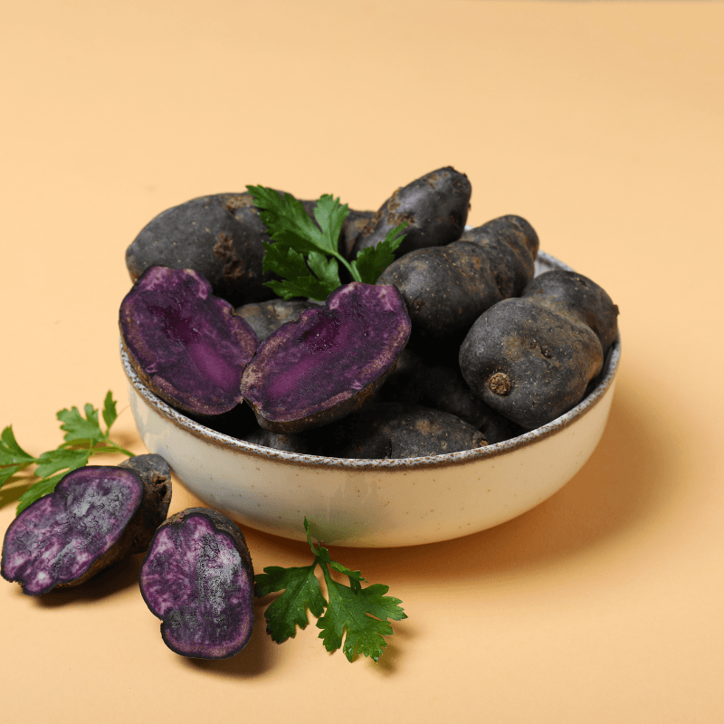 Whole and halved Purple Majesty potatoes in a bowl