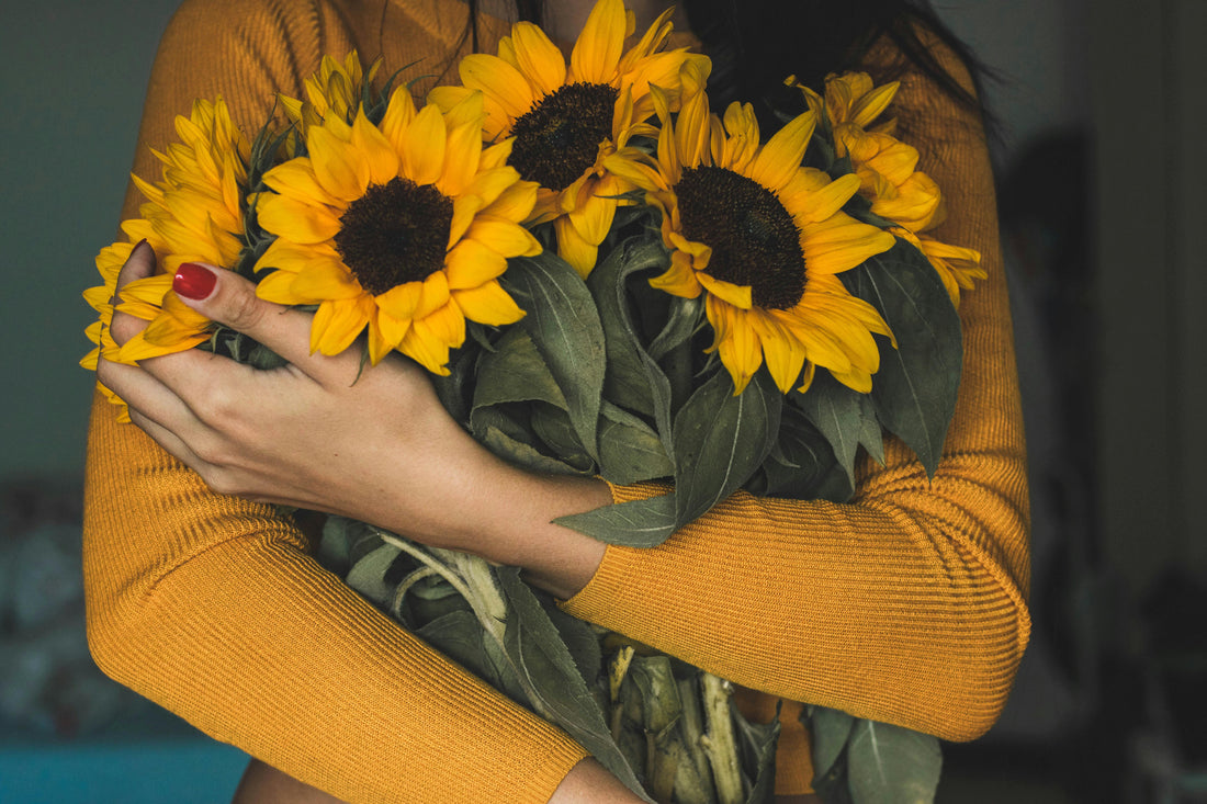 Person holding a large bouquet of sunflowers