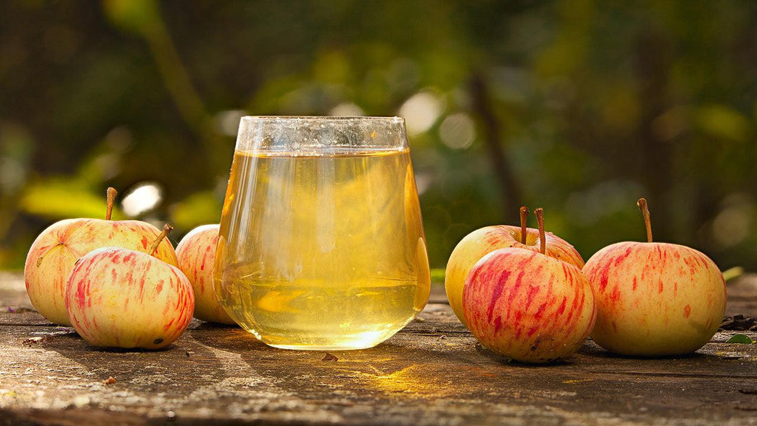 Jar of pale apple juice beside fresh apples