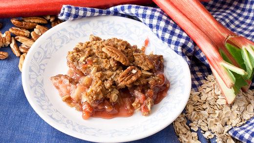 Bowl of rhubarb crisp beside fresh stalks