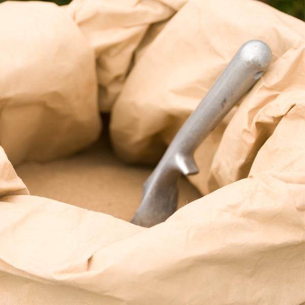 Metal hand trowel resting in an open paper bag
