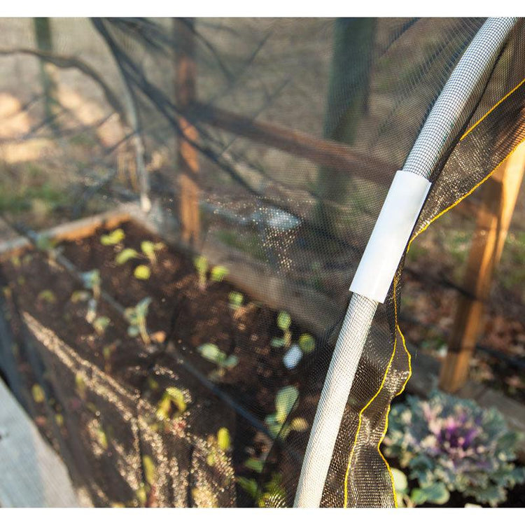 White shade cloth hanging beside garden plants