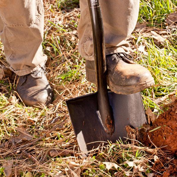 Person digging soil with a long-handled shovel