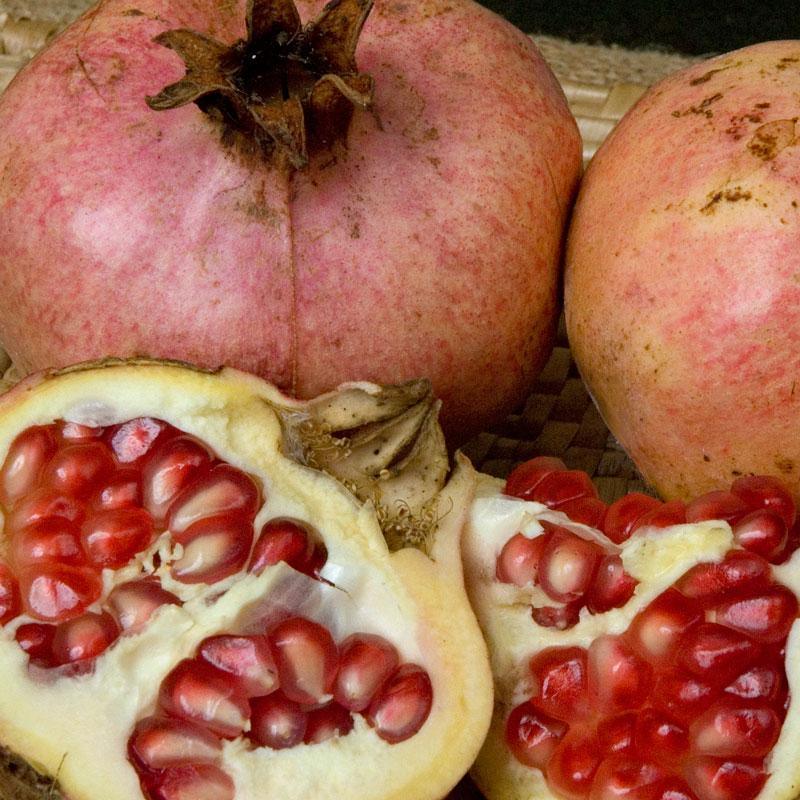 Whole and opened pale pink pomegranates with red arils