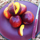 Red-skinned nectarines on a plate with a sliced piece and knife