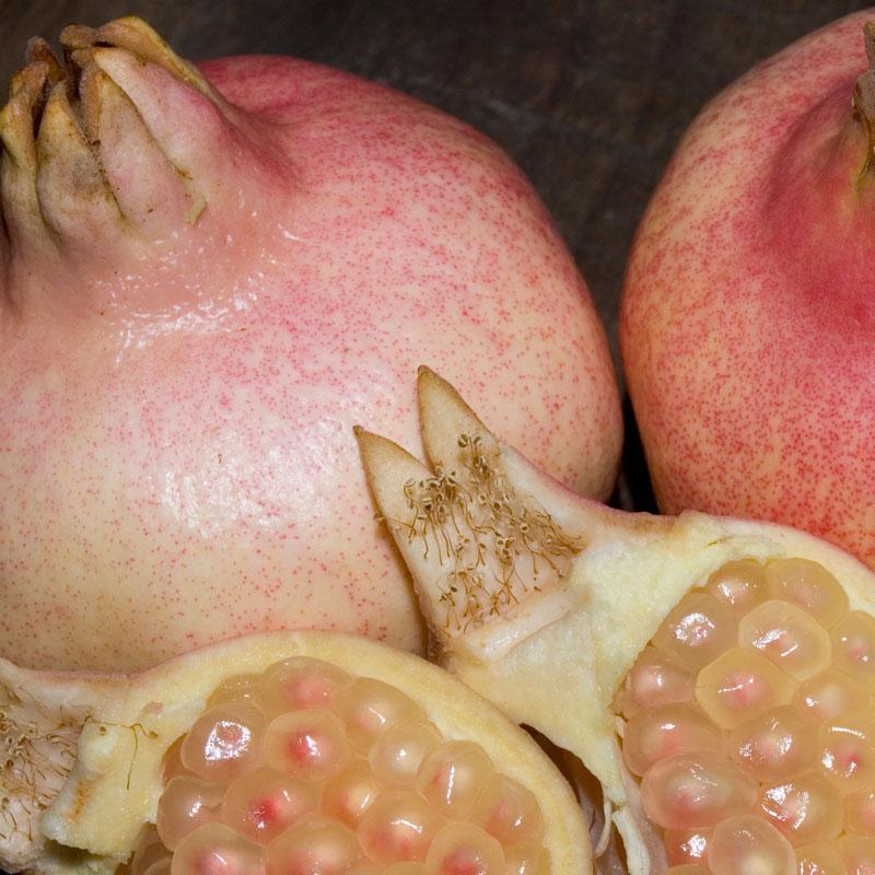 Whole and opened pale pink pomegranates with light pink arils