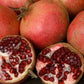 Whole and halved red pomegranates with dark red arils