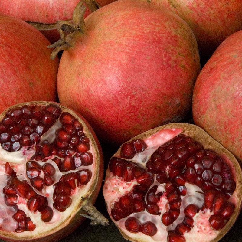 Whole and halved red pomegranates with dark red arils